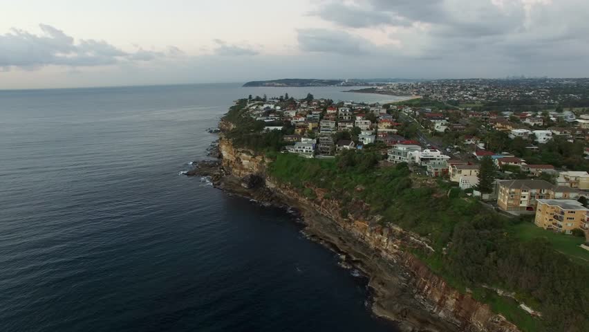 High angle slow pan across the cliffs of Dee Why to Dee Why beach.