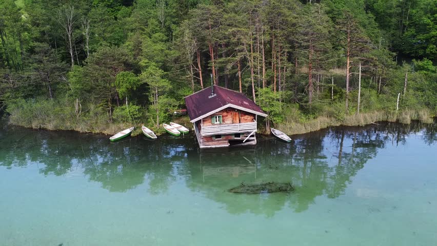 Drone footage of wooden cabin at the natural lake