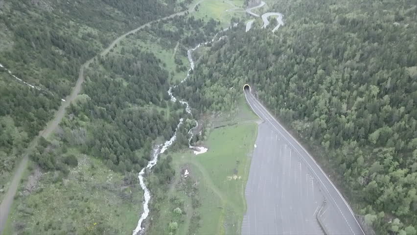 Road goes into a tunnel in the middle of the green meadow