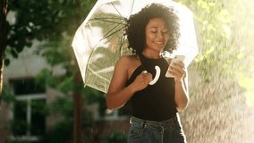Curly young african woman hold smartphone scrolling social media texting browsing online under umbrella while rain drops falling at sunset park Pretty student relax enjoying great rainy day outdoors - Powered by Shutterstock - Get 15% off with code: PIKWIZARD15