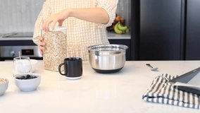 A woman cooks homemade granola standing in the kitchen. Video recipe, step 1