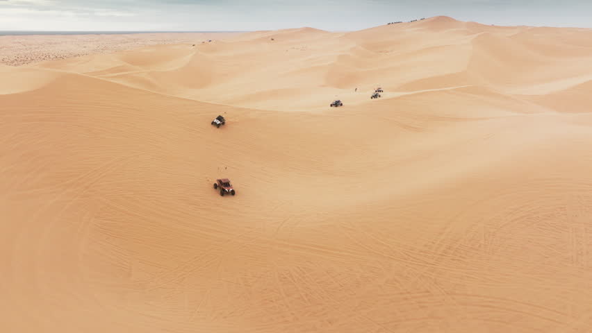 Group of four wheel drive vehicles competing on dunes. Aerial view of ATV buggy sport car riding fast by sand dunes. Extreme sport outdoor hobby on weekend day. Sport recreation concept for men 4K Royalty-Free Stock Footage #1104123279