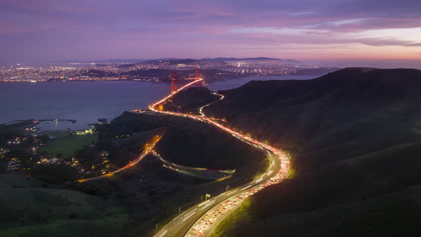 4K drone time lapse San Francisco California Skyline. Aerial hyperlapse traffic flow toward the Golden Gate Bridge at night illumination with scenic sunset sky on motion background. Downtown cityscape