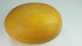 Fresh yellow melon lies on a white table.