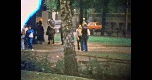 People walk in green park in rainy summer. People crowd walking, communicate on street outdoors. City life in park nature. Vintage color film. Travel, weekend archive. Retro 1980s Vilnius Lithuania