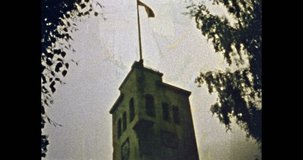 Lithuania flag fluttering on blue sky over clock tower building in summer outdoors. National Lithuanian flag waving. Vintage color film. Travel archive. Retro 1980s Vilnius Lithuania. Historic video