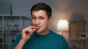 Portrait of Adult Man Eating Sweet Food and Looking at Camera. Real Person on Diet Consuming Delicious Cookie as Lunch Snack. Confident Male Inside Cozy Living Room Alone with Savory Sugary Fastfood - Powered by Shutterstock - Get 15% off with code: PIKWIZARD15