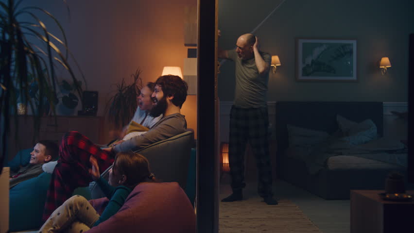 Happy family watch movie late at night. Elderly man with insomnia, irritated by noisy neighbors, screams, knocks on the wall, tries to sleep. Apartment without sound insulation. Neighbourhood concept. Royalty-Free Stock Footage #1104139217