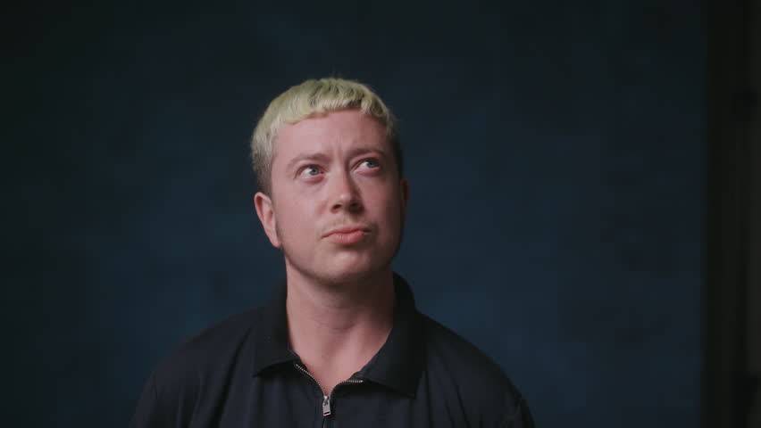 Transgender man facing camera with blue studio backdrop | Shutterstock HD Video #1104148099