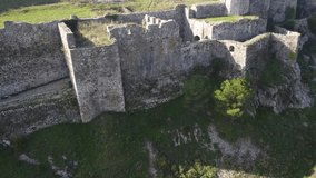 Stone Rozafa Castle in Scodra Albania. Waving Albanian flag. Fortress citadel on hill against city and the river background. Drone video. Bird eye view.