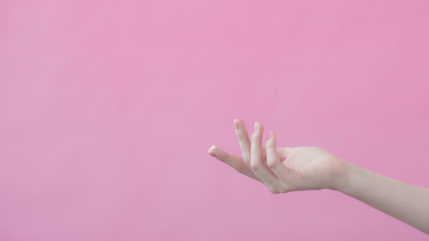 Female model lifts her hand with a drop of moisturizer on her forefinger. The concept of a moisturizer ad. Pink background Beauty Collection
