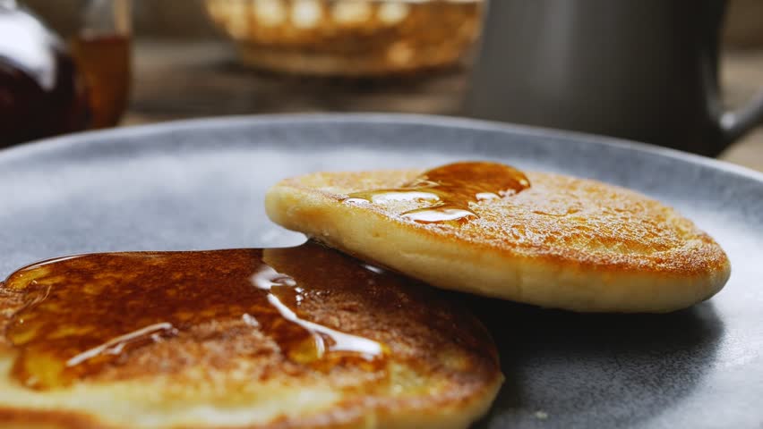 Homemade pancakes in a gray plate are poured with a thin stream of slow motion honey. Medium plan. Royalty-Free Stock Footage #1104163523