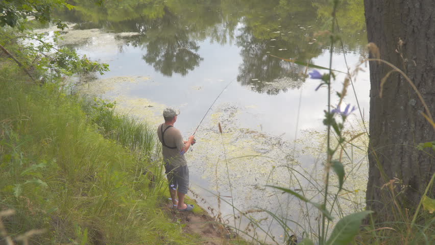 A fisherman is fishing with a light spinning from the shore. Spinningist on the shore