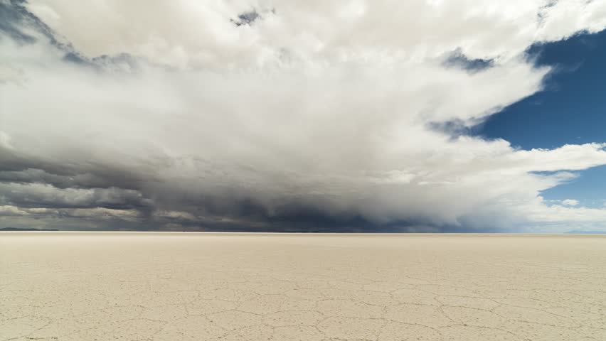 Uyuni Salt Flats on Sunny Day. Salar De Uyuni. Altiplano, Bolivia. Dry Season. Dramatic Beautiful Clouds on the Sky. Hexagonal Salt Formations and Crack Patterns. Wide Shot. Time Lapse