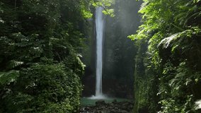 Drone shoot. Waterfall hidden in tropical rainforest jungle,  falling water hitting water surface, some huge rocks seeable in through splashes. Lush green leaves is moving from the wind. Philippines - Powered by Shutterstock - Get 15% off with code: PIKWIZARD15