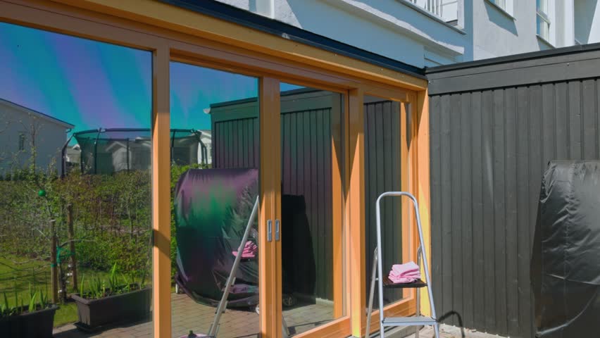 Close-up view of facade of villa with panoramic windows and prepared window cleaning supplies. Sweden.