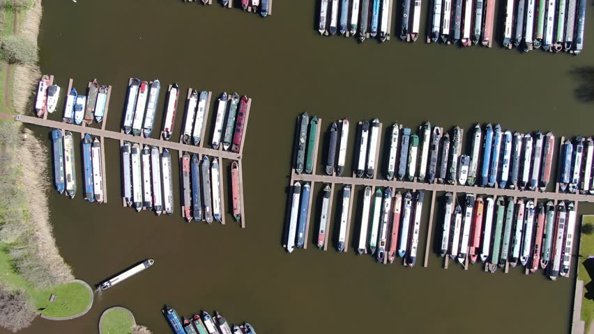 Aerial drone shot of canal narrow boat barge travelling into a marina dock harbour