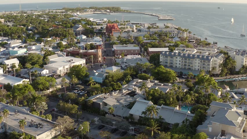 Aerial view of Key West, Florida landscape cityscape with Mallory Square and hotels, restaurants, and businesses with fishing boat in the harbor during golden hour sunset - 4K Drone