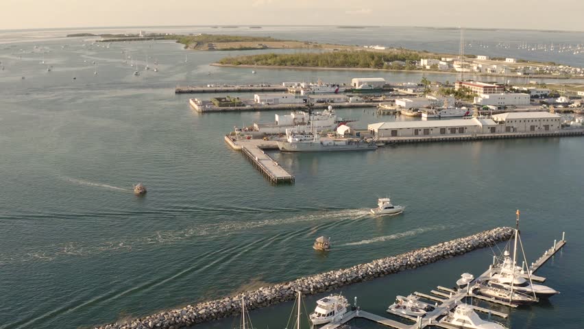 Fishing charter boat driving into harbor in Key West, Florida landscape with boat slips in yacht club during golden hour sunset - 4K Drone