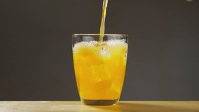 Orange soda is pouring into a glass with ice cube close-up on table. Orange soda. B roll Slow motion 4k. - Powered by Shutterstock - Get 15% off with code: PIKWIZARD15