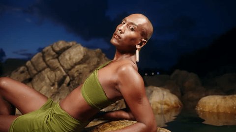 Gender fluid black person poses gracefully in creek waist deep in natural still water pool. Queer ethnic fashion model in long revealing clothes stands in the middle of crystal clear lake Adlı Stok Video