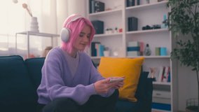 Woman with colored hair watching music video or movie on smartphone at home