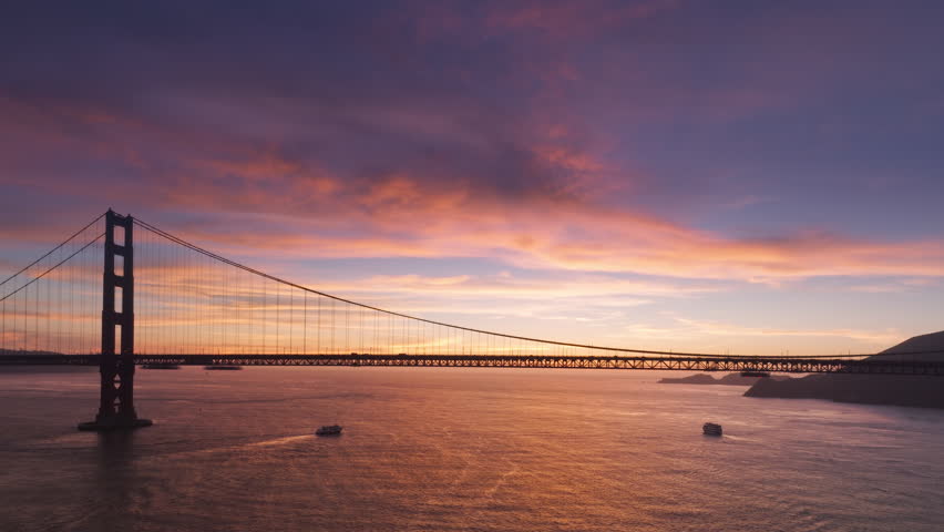 Breathtaking panorama of sunset sky with pink purple clouds on background of world famous Golden Gate Bridge silhouette. Aerial suspension bridge San Francisco landmark at cinematic sunset 4K USA
