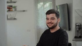 A handsome caucasian man is drinking freshly squeezed orange juice with vitamin C. A European dark-haired guy in a black t-shirt is drinking a healthy drink from a glass cup. Healthy lifestyle - Powered by Shutterstock - Get 15% off with code: PIKWIZARD15