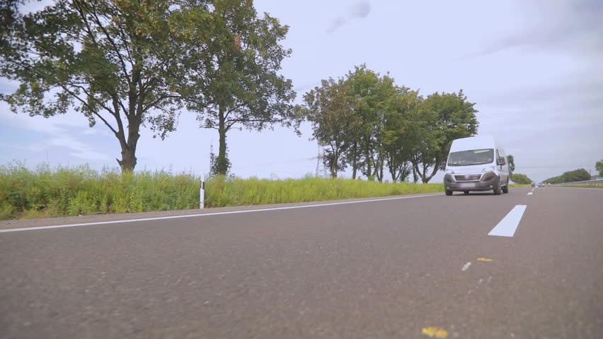White delivery van or service van driving down the highway on a sunny day. Fast delivery or service concept.