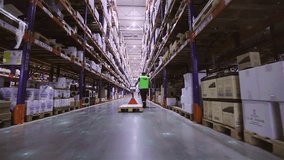 Digitalization of production. A worker is carrying a rokla through a large warehouse. The worker walks through the warehouse. Futuristic production concept. - Powered by Shutterstock - Get 15% off with code: PIKWIZARD15