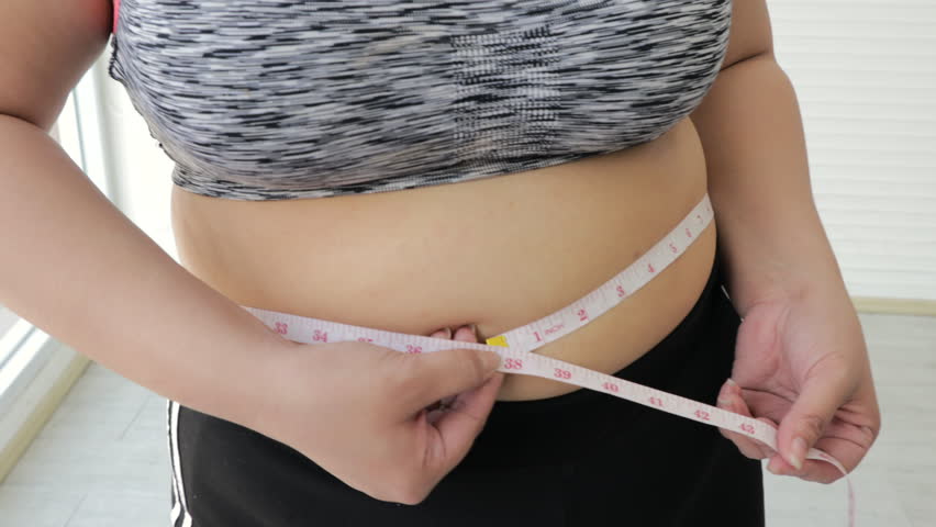 A Fat Woman Measures Her Waist with a Measuring Tape, Close-up