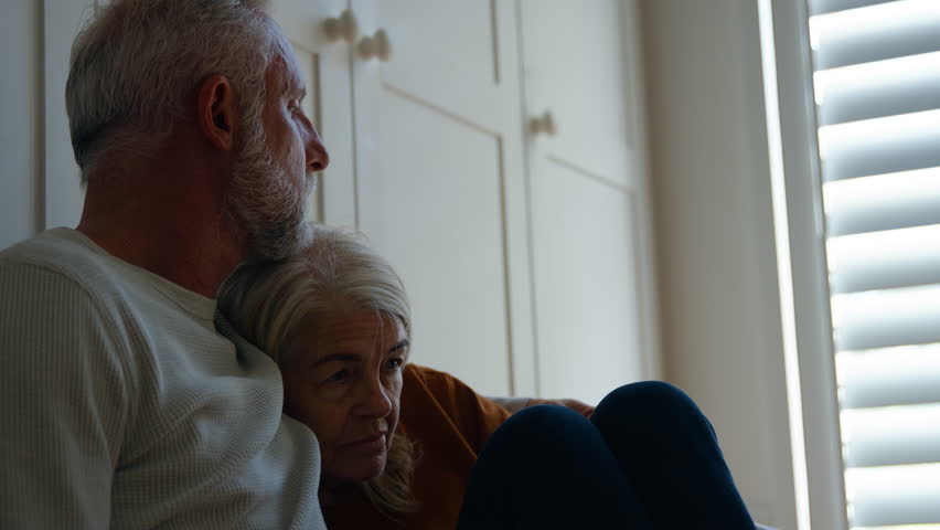 Handheld shot of unhappy senior woman suffering with mental health problems sitting on floor of room at home being supported by husband - shot in slow motion Royalty-Free Stock Footage #1104187985
