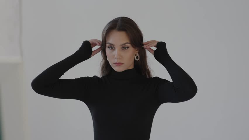 back stage professional female model in black white wall. pretty young woman long brunette hair model photo shoot. slim girl student striking expressive pose for camera shoot. portrait face beauty eye