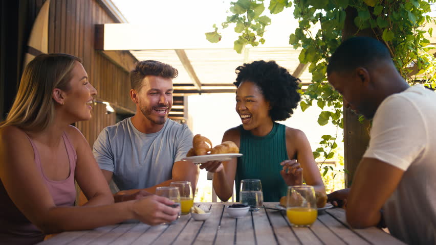 Smiling group of smiling friends on holiday eating breakfast outdoors together - shot in slow motion Royalty-Free Stock Footage #1104190311