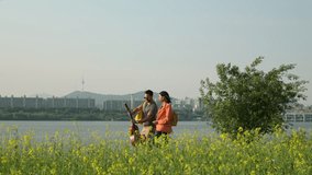 Happy Young Couple Walking Riverside with Yellow Flower Field in Foreground at Seorae Island At Sunset. Picnic in a Park Concept - Powered by Shutterstock - Get 15% off with code: PIKWIZARD15
