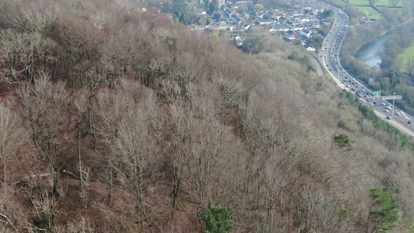 Drone shot of Castell Coch (translated: Red Castle) historic destination near Cardiff, Wales, appearing from behind forested woodland hill in late winter early spring