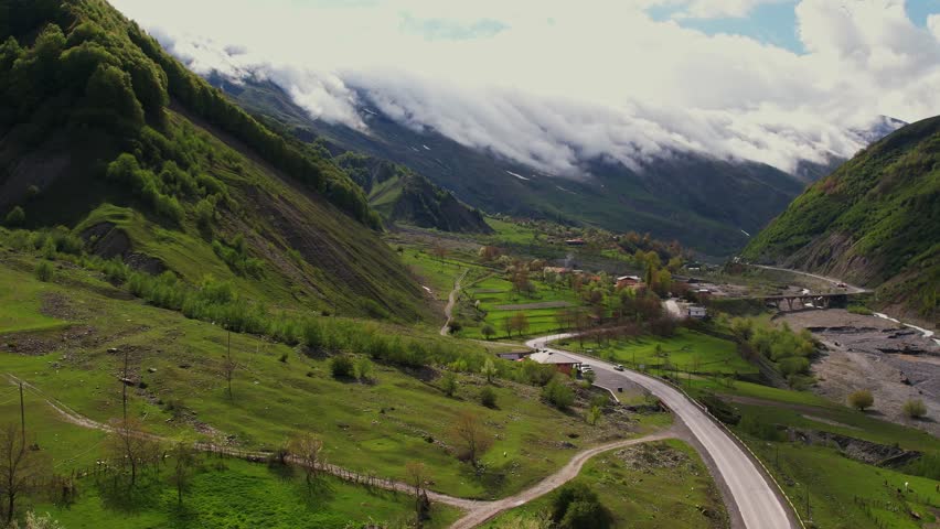 Aerial drone view of heavy fog clouds flowing over the mountain. Foggy clouds hanging in the mountains. Beautiful mountain view of the snow-capped peaks near Gudauri, Georgia.
