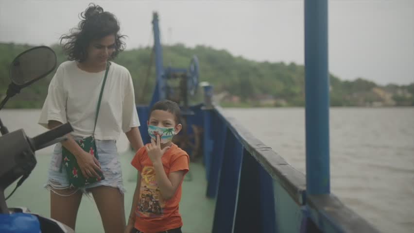 A young girl and a young boy are laughing and talking to each other in a cheerful mood on the deck of a ship.