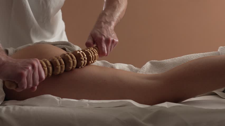 Unknown Caucasian woman having madero therapy massage anti-cellulite treatment by professional therapist holding wooden tools in hands in studio or salon slow motion Royalty-Free Stock Footage #1104200151