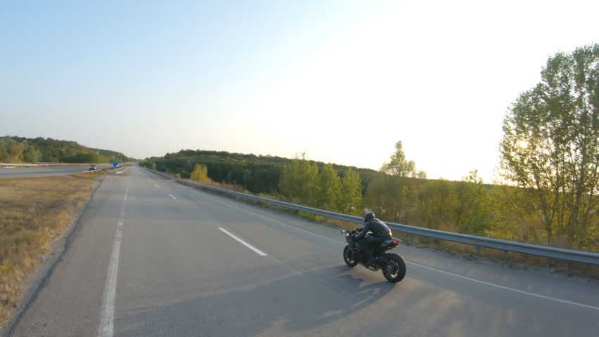 Biker riding on modern sport motorbike at highway during sunny autumn day. Motorcyclist racing his motorcycle on country road. Guy drive bike during trip. Concept of freedom and adventure. Aerial shot