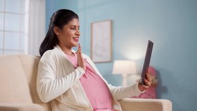 Happy pregnant woman talking with doctor using digital tablet at home - concept of long distance relationship, telehealth and virtual consultation