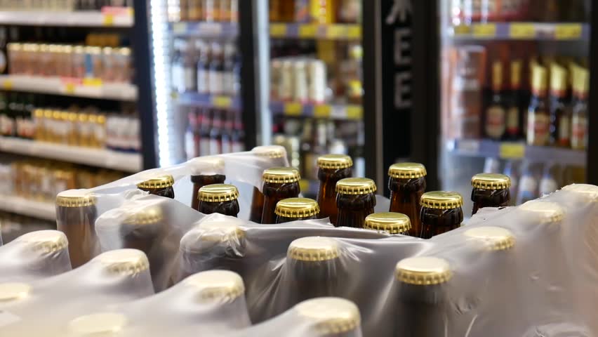 An opened pack of beer bottles in alcohol department and a buyer takes two of them
