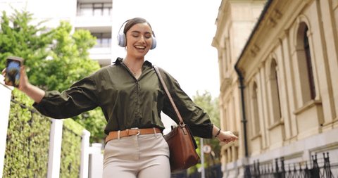 Happy, dance and woman in city, headphones and celebrate in street, cheerful and inspiration. Female person, lady and girl with headset, dancing and movement in town, listening to music and radio Stockvideó