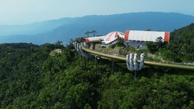 Aerial  4K footage of the Golden Bridge in Ba Na hills, Da Nang, Vietnam. Lifted by two giant concrete hands. Iconic world famous bridge in the mountains