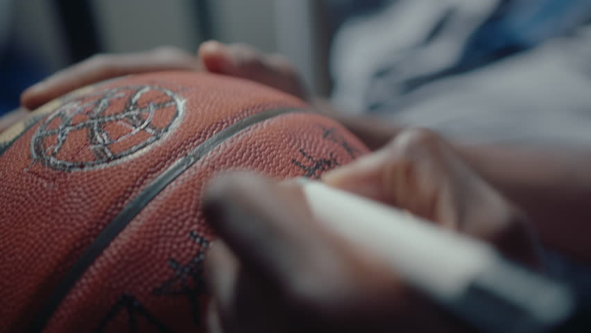 Hands of black basketball athlete making a sign or autograph on a ball with marker pen. Close-up impersonal shot Royalty-Free Stock Footage #1104210559