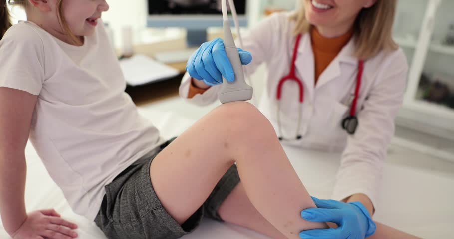 Doctor conducts ultrasound examination of knee joint in child in clinic Royalty-Free Stock Footage #1104214175