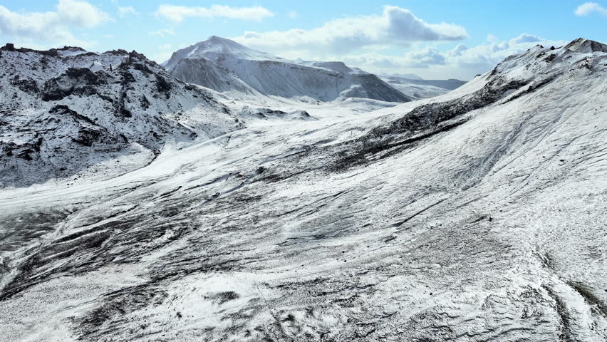 Aerial view of snow mountain range landscape in Iceland under blue sky. Epic panorama background 4k winter drone footage.