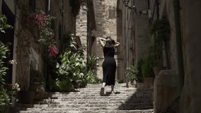 A young spanish woman collects her hair as she climbs some urban stone stairs in a sunny day.
