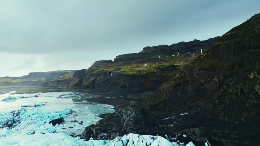 Aerial view of vatnajokull glacier cap, natural blue glacier lagoon forming on frozen lake in icelandic landscape. Massive arctic icebergs floating, icy land. 60 fps video.