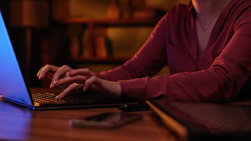 A woman works on a computer, a close-up of the keyboard. Text message for customers. Businesswoman writing a business letter at work. Cinematic light, evening, stylish office.